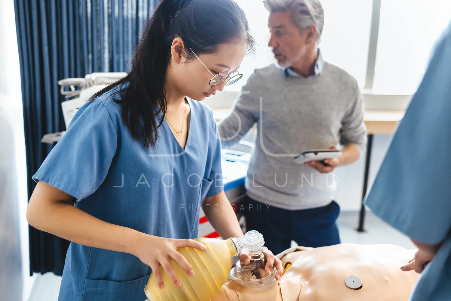 Asian nursing student learns how to use a bag valve mask on a patient simulator