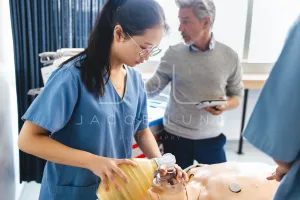 Asian nursing student learns how to use a bag valve mask on a patient simulator